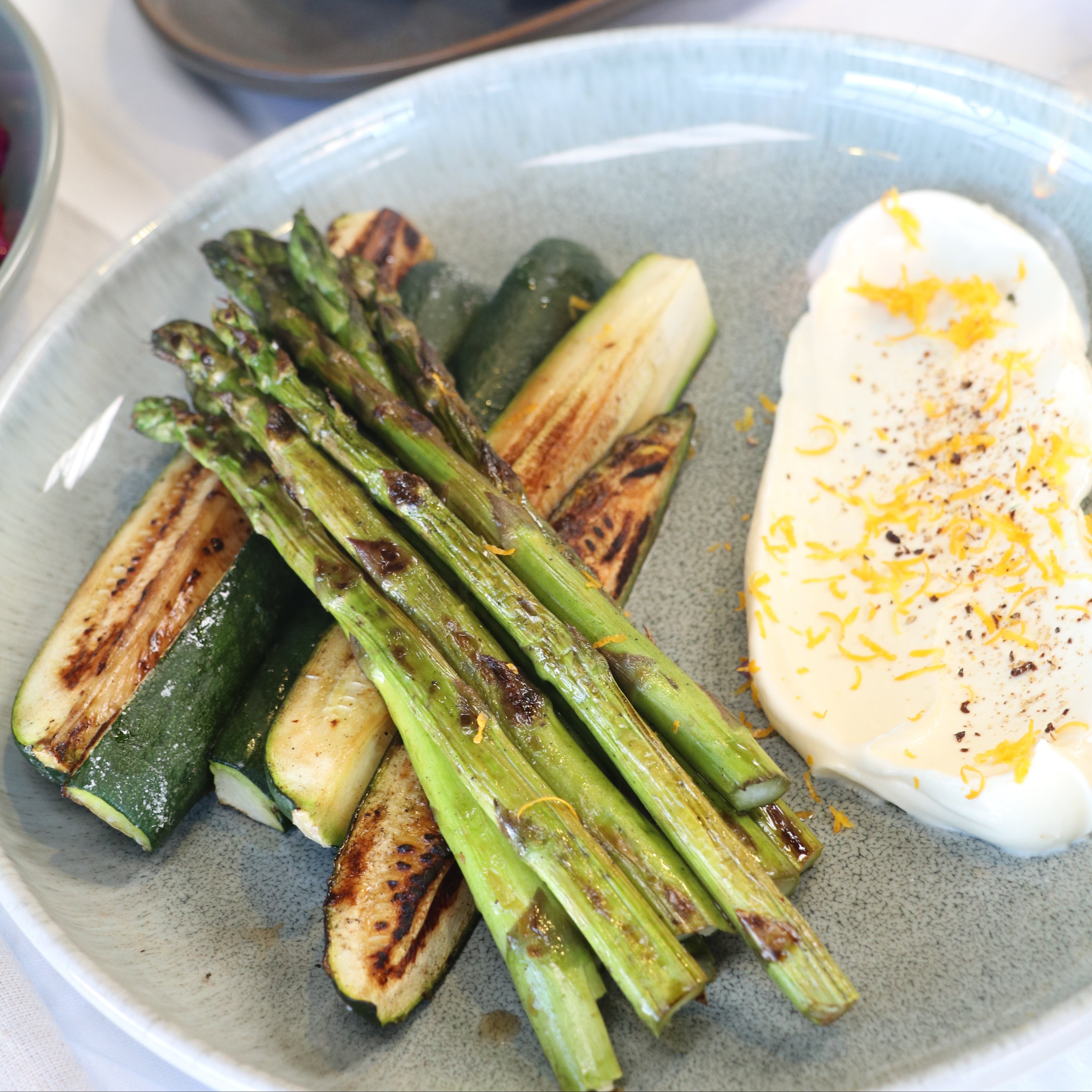 Plate of roasted vegetables including zucchini and asparagus, with ricotta side