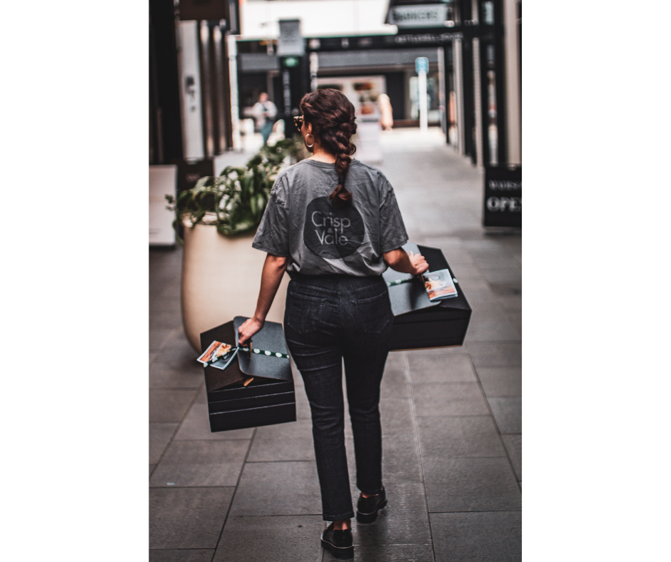 Person holding multiple show cases in an open air shopping mall