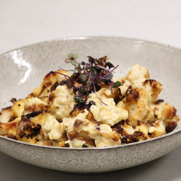 cauliflower and cheese meal cooked and presented in bowl with micro-greens on top. white background