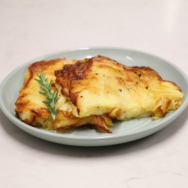 Dauphinoise potato ready meal from crisp and vale. Cooked, golden crispy and presented on small dis  with rosemary garnish