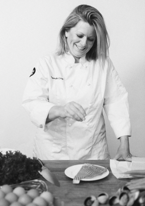 Black and white photo of a chef preparing food in a kitchen.